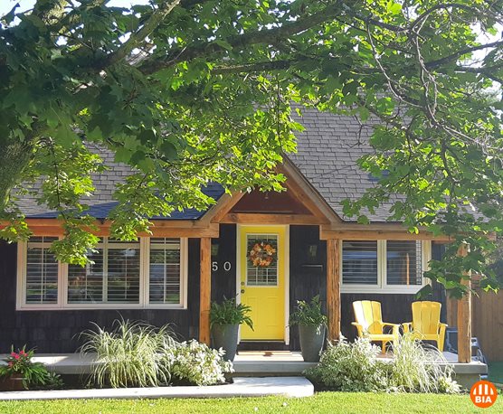 A small suburban house with front porch and overhanging tree
